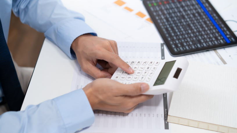 Pessoa usando calculadora e documentos.